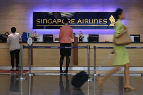 People walk past a Singapore Airlines ticketing counter at Changi Airport in Singapore May 7, 2014.