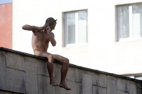 Artist Pyotr Pavlensky cuts off a part of his earlobe while sitting on the wall enclosing the Serbsky State Scientific Center for Social and Forensic Psychiatry during his protest action titled &quot;Segregation&quot; in Moscow October 19, 2014. Pavlensky
