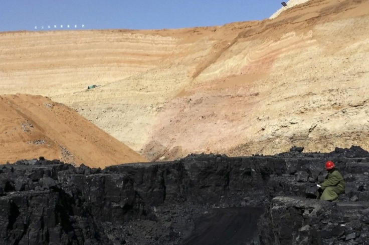A mine worker looks at stacks of coal in an open-cast steam coal mine located in the Ordos mining district, Inner Mongolia Autonomous Region, March 14, 2014. China's top producing coal province of Inner Mongolia, where Ordos is located, is in crisis. Tumb