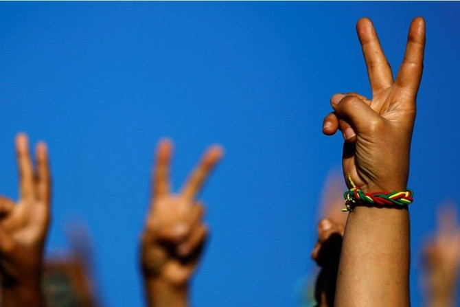 A Turkish Kurdish woman sports a wrist band with the Kurdish colours as she gestures with others