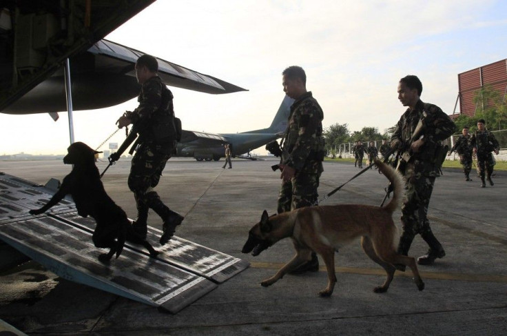 Filipino soldiers with K9 sniffing dogs board a military plane at the Villamor air base in Pasay city, metro Manila October 7, 2014, as they embark on a search operation for the hideout of Abu Sayyaf group, an Al Qaeda-linked terrorist group who are belie