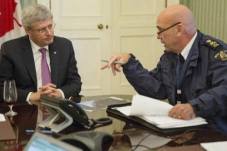 Canadian Prime Minister Stephen Harper (L) is briefed by Royal Canadian Mounted Police (RCMP) commissioner Bob Paulson following a shooting incident on Parliament Hill in Ottawa in this October 22, 2014 handout photo. A gunman shot and fatally wounded a s