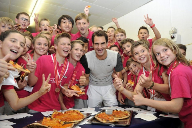 Switzerland&#039;s Roger Federer poses together with the tournament&#039;s ball boys and girls as they eat pizza, after he won his final match against Belgium&#039;s David Goffin at the Swiss Indoors ATP tennis tournament in Basel  October 26, 2014. REUTE