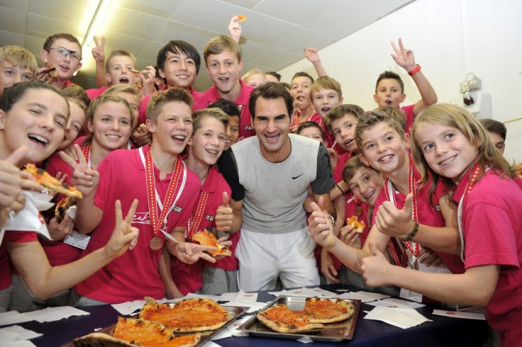 Switzerland's Roger Federer poses together with the tournament's ball boys and girls as they eat pizza, after he won his final match against Belgium's David Goffin at the Swiss Indoors ATP tennis tournament in Basel October 26, 2014. REUTE
