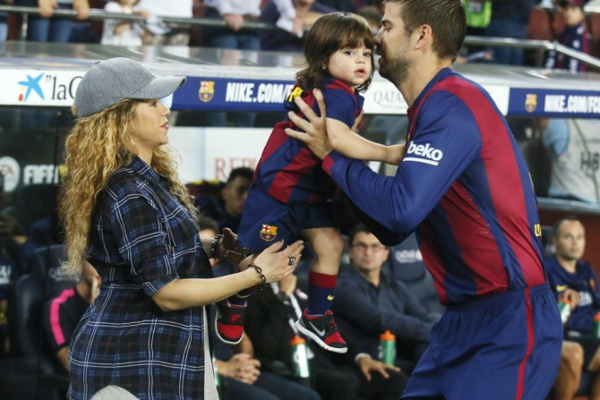 Singer Shakira (L) passes their son Milan to Barcelona's Gerard Pique before the Spanish first division soccer match between Barcelona and Eibar at Camp Nou stadium in Barcelona October 18, 2014. REUTERS/Albert Gea