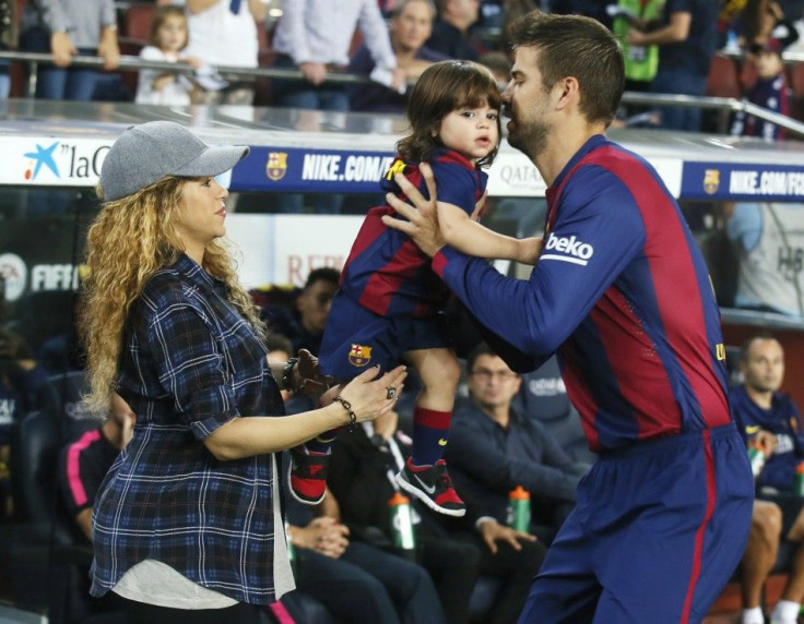 Singer Shakira (L) passes their son Milan to Barcelona's Gerard Pique before the Spanish first division soccer match between Barcelona and Eibar at Camp Nou stadium in Barcelona October 18, 2014. REUTERS/Albert Gea