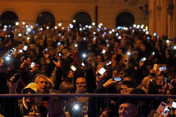 People holds up their mobile phones as they protest against new tax on Internet data transfers in centre of Budapest October 26, 2014. REUTERS/Laszlo Balogh
