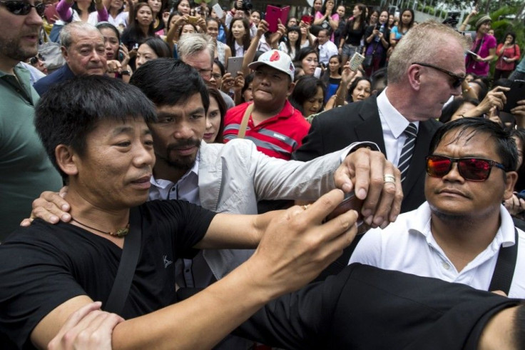 Boxer Manny Pacquiao (C) of the Philippines poses for a selfie with a fan during his tour in Hong Kong October 26, 2014. Pacquiao is on tour ahead of defending his WBO World Welterweight title on November 23 against Chris Algieri of the U.S. at the Veneti