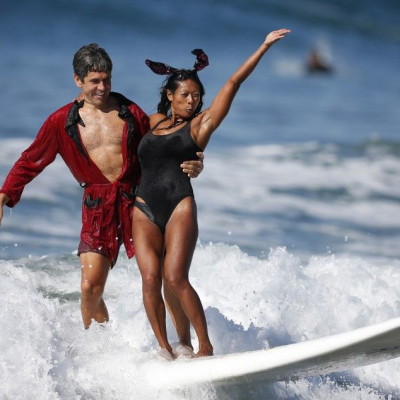 Jeremy Porfilio, 41, (L) and Tammy Mowery ride a wave dressed as Playboy founder Hugh Hefner and his ex-girlfriend Kendra Wilkinson