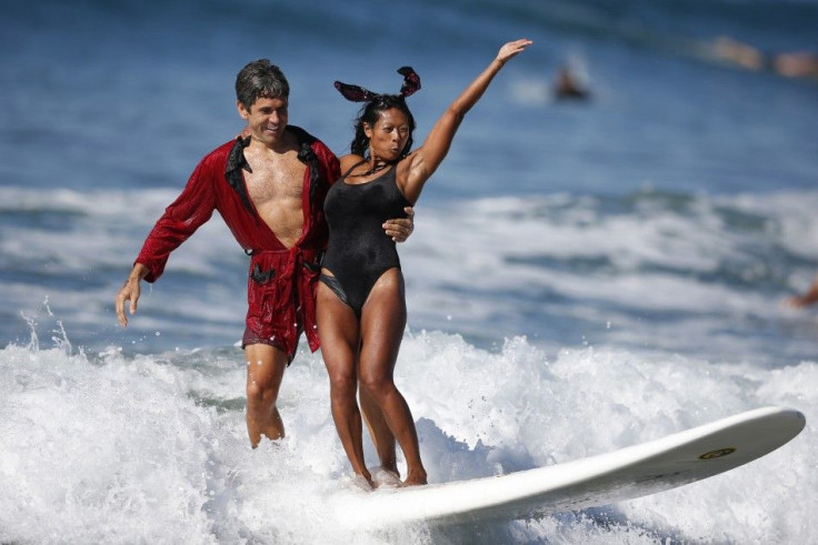 Jeremy Porfilio, 41, (L) and Tammy Mowery ride a wave dressed as Playboy founder Hugh Hefner and his ex-girlfriend Kendra Wilkinson