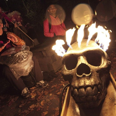 Revelers plays a drum in the rain beside a burning skull during the annual Parade of Lost Souls on the eve of Halloween