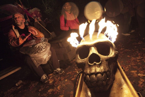 Revelers plays a drum in the rain beside a burning skull during the annual Parade of Lost Souls on the eve of Halloween