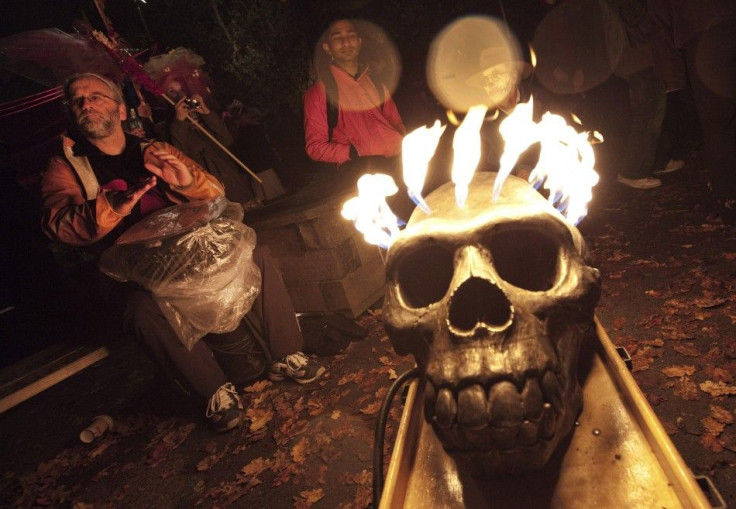 Revelers plays a drum in the rain beside a burning skull during the annual Parade of Lost Souls on the eve of Halloween