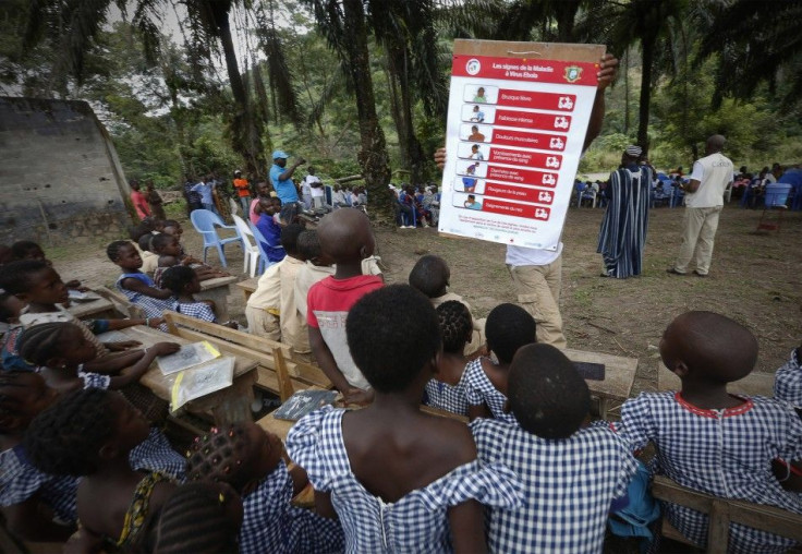 A man shows students a poster on the symptoms of Ebola during a United Nations Children's Fund (UNICEF) Ebola awareness drive in Gueupleu, Man, western Ivory Coast November 3, 2014.