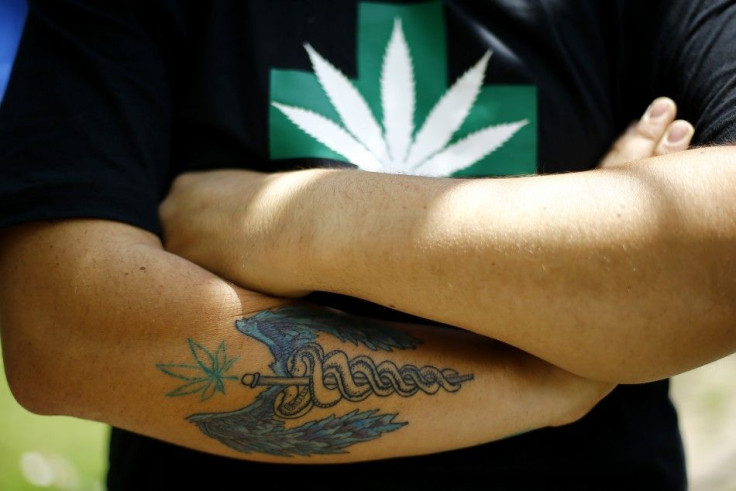 A man wearing a t-shirt with a marijuana leaf and a tattoo featuring a medicine symbol