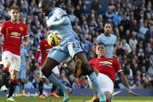 Manchester City's Yaya Toure (C) is challenged by Manchester United's Marcos Rojo during their English Premier League soccer match at the Etihad Stadium in Manchester, northern England November 2, 2014. 