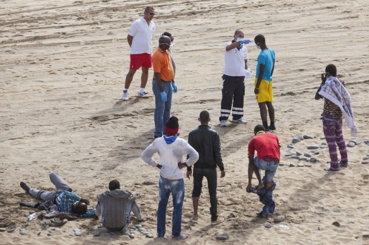 A medical worker (top, 3rd R) takes the temperature of a would-be immigrant at Maspalomas beach on Gran Canaria in Spain's Canary Islands November 5, 2014. Some 21 would-be immigrants arrived in a fishing boat on their way to European soil from Africa, Sp