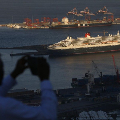 A visitor takes photographs of Cunard's cruise liner Queen Mary 2 as the ship sits berthed in Cape Town harbour in this picture taken January 27, 2014.