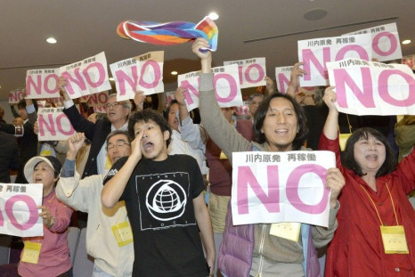 Protesters hold signs that read &quot;No to restarting Sendai nuclear plant&quot; in the public gallery of the prefectural assembly of Kagoshima, following the assembly&#039;s approval of the resumption of operations of two reactors of the Sendai nuclear 