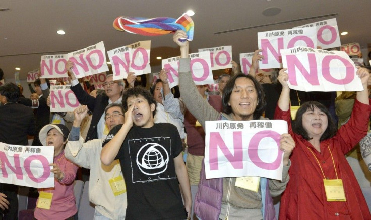 Protesters hold signs that read &quot;No to restarting Sendai nuclear plant&quot; in the public gallery of the prefectural assembly of Kagoshima, following the assembly&#039;s approval of the resumption of operations of two reactors of the Sendai nuclear 