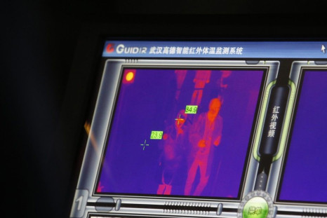 A monitor displays the body temperature of a passenger (R) arriving at the Beijing Capital International Airport October 30, 2014. China's capital will suggest to people returning from regions affected by Ebola to quarantine themselves at home for 21