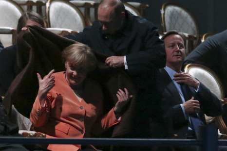Russia&#039;s President Vladimir Putin (C) places a shawl around German Chancellor Angela Merkel
