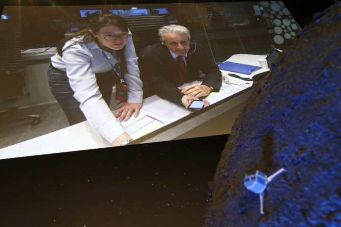 Paolo Ferri (R) Head of Rosetta Mission Operations, seen on a video projection behind a model of the Philae lander, reacts after the successful landing of the lander on comet 67P