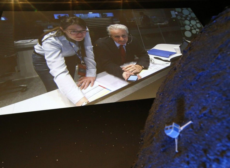 Paolo Ferri (R) Head of Rosetta Mission Operations, seen on a video projection behind a model of the Philae lander, reacts after the successful landing of the lander on comet 67P