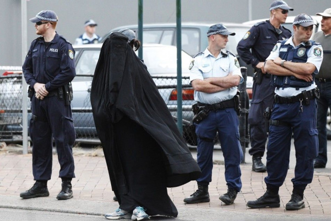 Police officers stand on guard next to a woman wearing a burqa