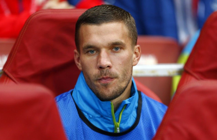 Arsenal's Lukas Podolski watches his team from the bench during their Champions League playoff soccer match against Besiktas at the Emirates stadium in London August 27, 2014.