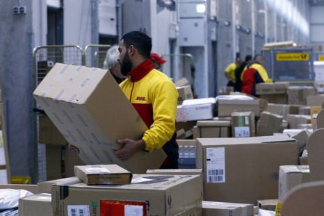 Workers load trucks with parcels at the new distribution centre of the German postal and logistics group Deutsche Post DHL in Berlin November 12, 2013. Deutsche Post posted a better-than-expected rise in quarterly operating profit as earnings at its domes