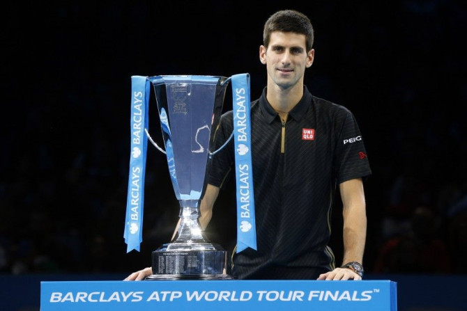 Novak Djokovic of Serbia stands behind the trophy after Roger Federer of Switzerland forfeited due to injury in the men's singles final at the ATP World Tour Finals at the O2 in London, November 16, 2014. REUTERS/Suzanne Plunkett