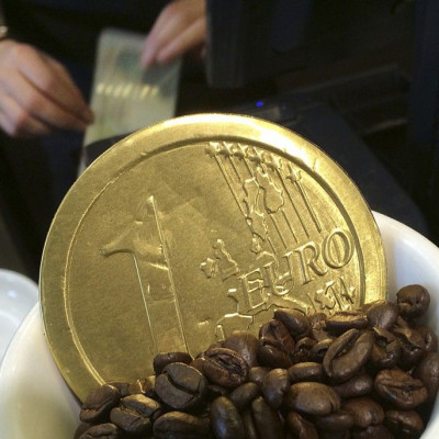 An employee uses a cash till, behind a chocolate shaped as a one Euro coin and placed for sale in a coffee cup, at a cafe in central London October 15, 2014.