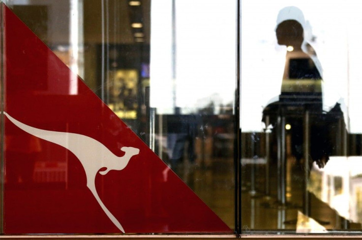 A passenger walks past a Qantas Airways emblem at the Sydney International Airport terminal July 18, 2014. 