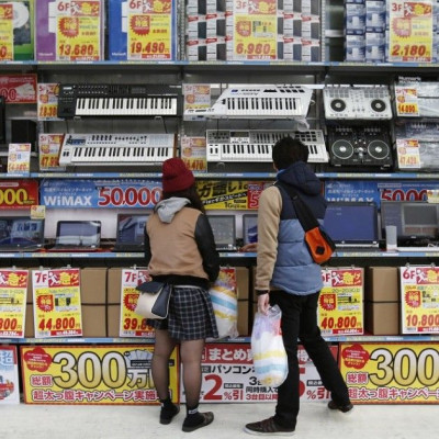 People try out laptops displayed at an electronics retail store in Tokyo November, 16, 2014. Japan's economy unexpectedly shrank an annualised 1.6 percent in July-September after a severe contraction in the previous quarter, likely solidifying the view th