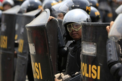 An Indonesian policeman holding his shield stands guard near the Constitutional Court in Jakarta August 21, 2014. Indonesian police fired tear gas to disperse thousands of protesters outside the country's top court in Jakarta on Thursday, as judges starte