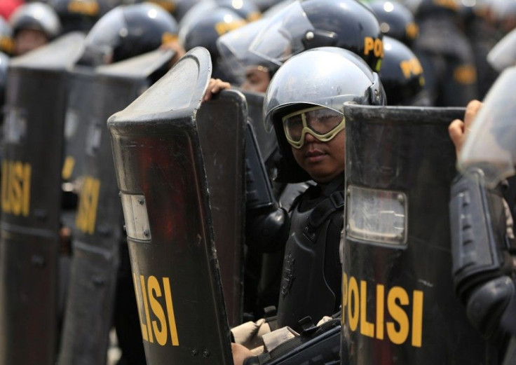 An Indonesian policeman holding his shield stands guard near the Constitutional Court in Jakarta August 21, 2014. Indonesian police fired tear gas to disperse thousands of protesters outside the country's top court in Jakarta on Thursday, as judges starte