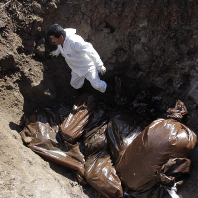 A morgue worker stands next to bags containing unidentified bodies at a grave at Divino Para?so cemetery in Tegucigalpa October 4, 2014. The bodies of 29 people, who were not claimed from the city morgue and were mostly killed in drug-related incidents an