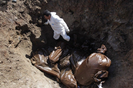 A morgue worker stands next to bags containing unidentified bodies at a grave at Divino Para?so cemetery in Tegucigalpa October 4, 2014. The bodies of 29 people, who were not claimed from the city morgue and were mostly killed in drug-related incidents an