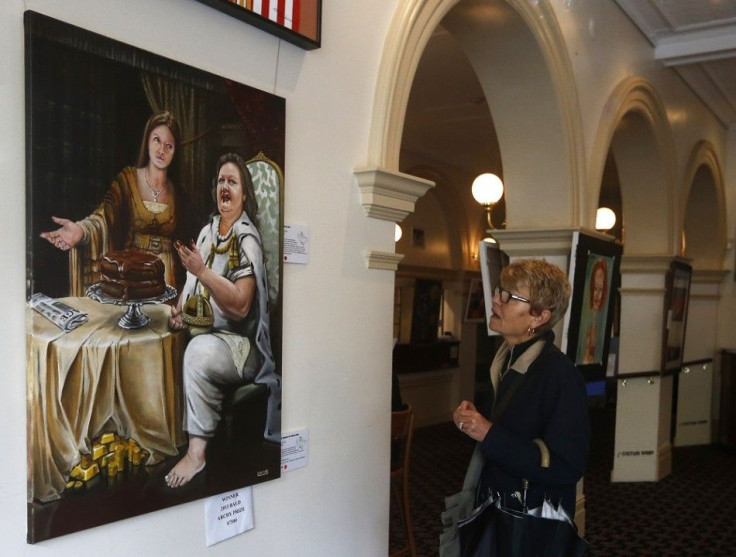 A woman looks at the painting 'The Banquet of Gina and Ginia' by artist Warren Lane at the Bald Archy Prize exhibition in Sydney April 6, 2013. The portrait depicting Australia's iron ore magnate Gina Rinehart eating a chocolate cake as her daughter Ginia
