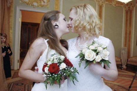 Two brides kiss during their wedding ceremony to each other at the wedding registry office in St. Petersburg
