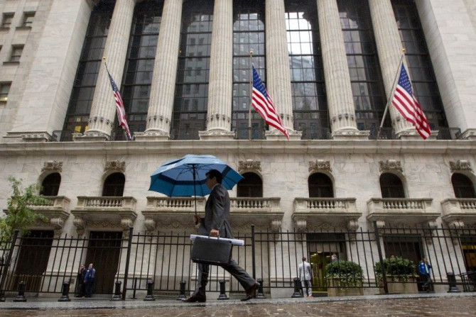 A man carries an umbrella in the rain as he passes the New York Stock Exchange October 16, 2014. Stocks on Wall Street rebounded from earlier lows on Thursday to trade little changed as a flurry of economic reports helped ease fears a weakening global eco