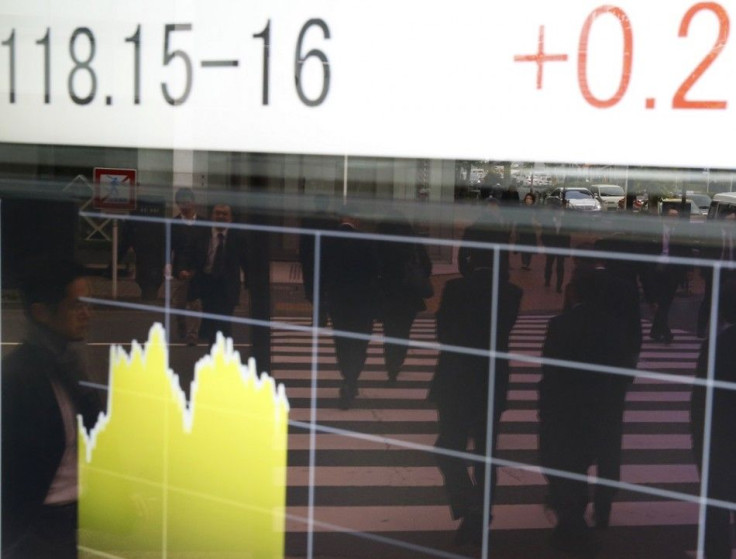 People are reflected on an electronic board showing the Japanese yen's exchange rate against the U.S. dollar outside a brokerage in Tokyo November 20, 2014. Asian stocks mostly fell on Thursday as fresh data signalling a further loss of momentum in China'