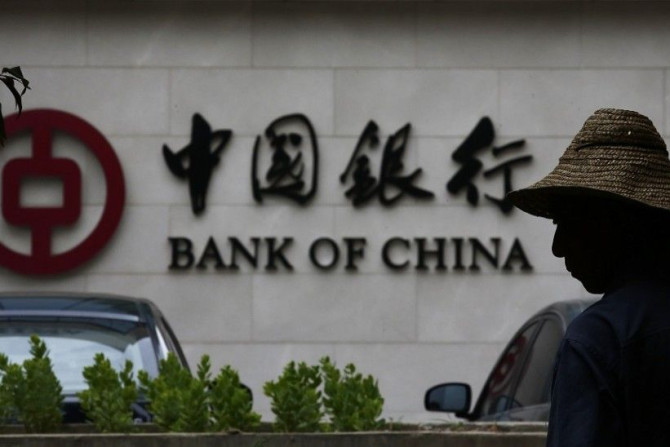 A man is silhouetted in front of a Bank of China's logo at its branch office in Beijing July 14, 2014. China's central bank is looking into allegations by a state broadcaster that Bank of China, the country's fourth largest lender, has been laundering mon