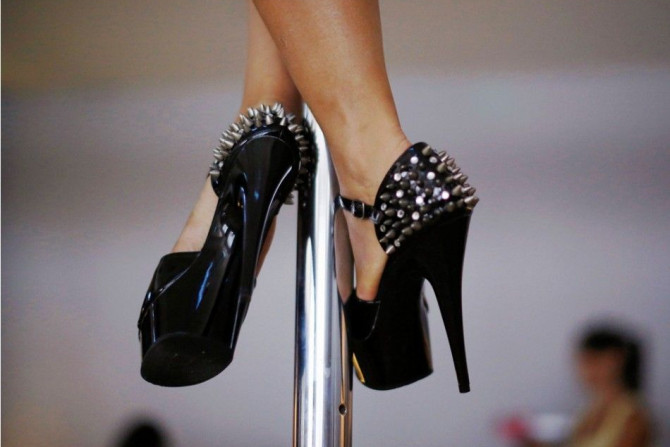 A woman wears spiked stilettos as she practises a pole dancing move during an International Women&#039;s Day event