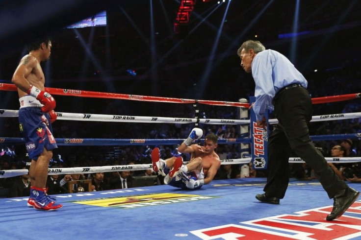 Chris Algieri (C) of the U.S. falls after taking a punch from Manny Pacquiao (L) of the Philippines during their World Boxing Organisation (WBO) 12-round welterweight title fight at the Venetian Macao hotel in Macau November 23, 2014.