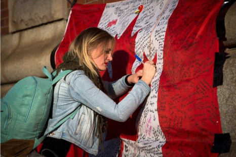 A woman writes a message on a Canadian flag at a makeshift memorial in honour of Cpl. Nathan Cirillo