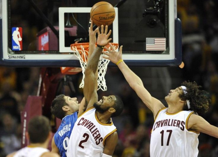 Nov 24, 2014; Cleveland, OH, USA; Orlando Magic center Nikola Vucevic (9) reaches for a rebound against Cleveland Cavaliers guard Kyrie Irving (2) and center Anderson Varejao (17) in the third quarter at Quicken Loans Arena.