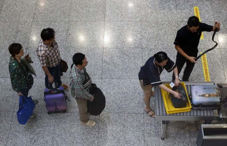 A passenger removes his belt as he puts his belongings into an X-ray machine for screening by airport security at the departure hall of the Kuala Lumpur International Airport 