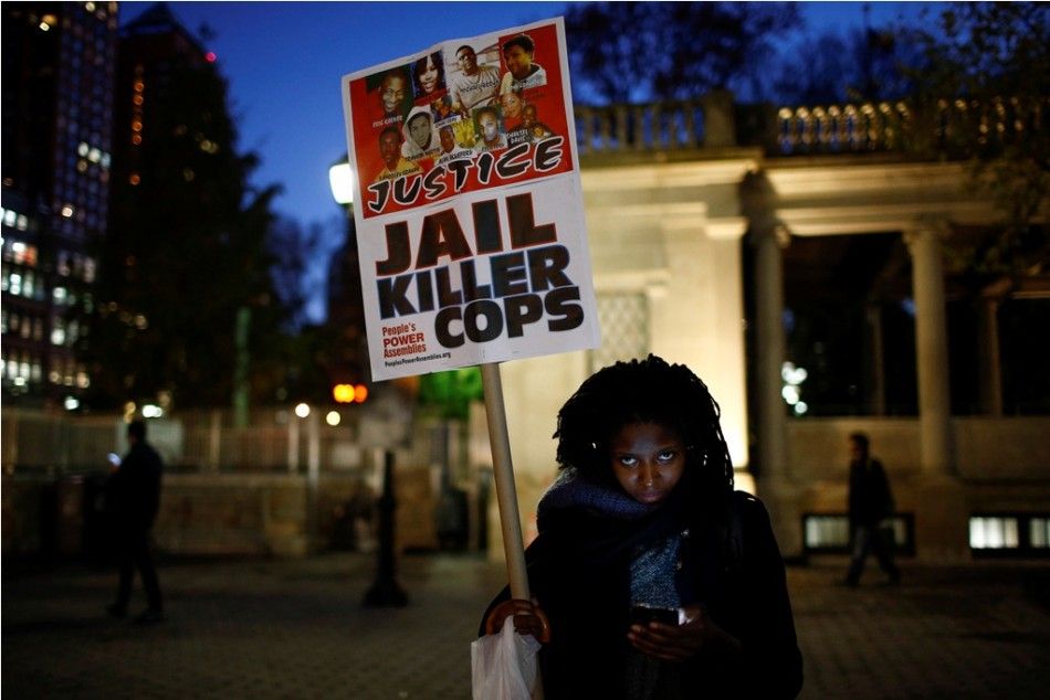 A woman holds a sign with images of Eric Garner and Michael Brown, among others, as protesters begin to rally in New York